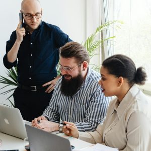 A diverse group of professionals engaged in a collaborative team meeting at a modern office with laptops and mobile phones.